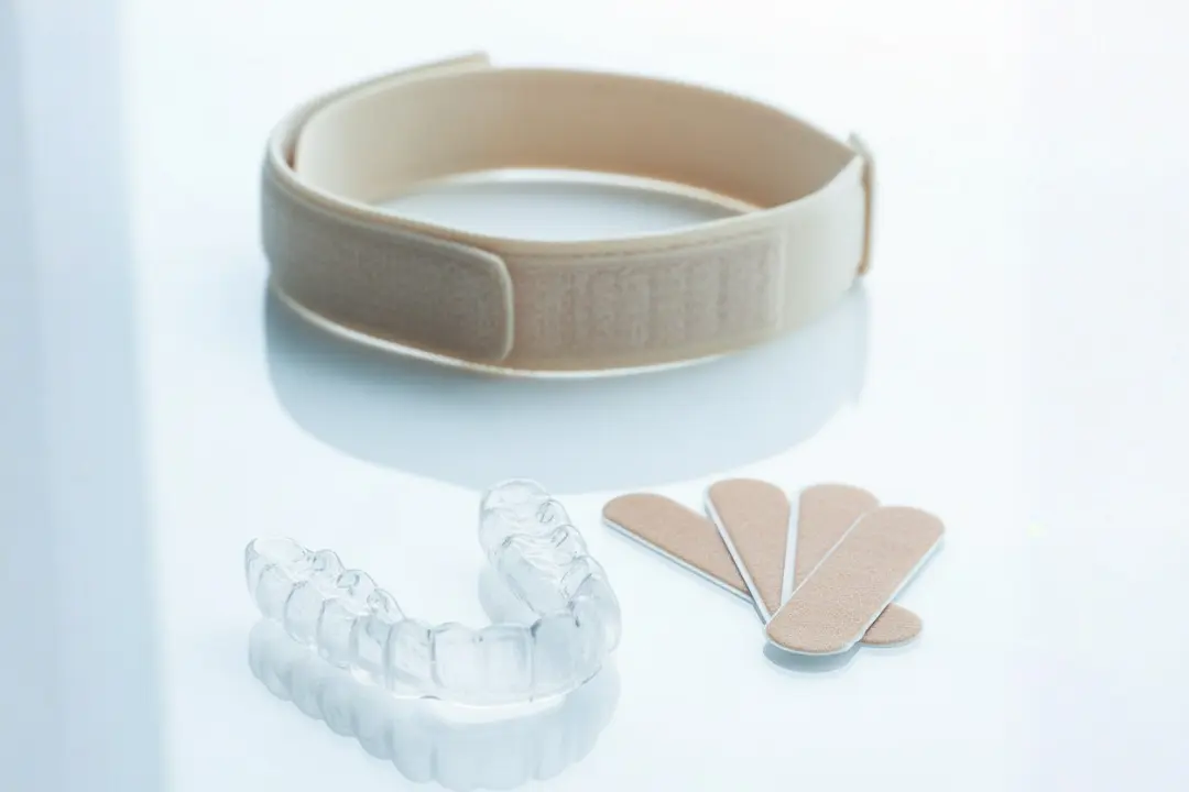 CPAP mask and chin strap setup beside nasal strips and mouthpiece