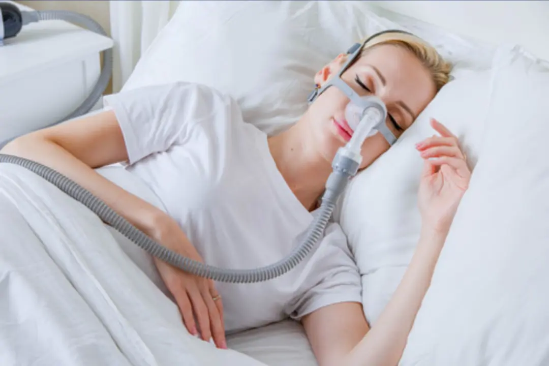 CPAP tube and humidifier beside quiet CPAP machine in soft blue lighting