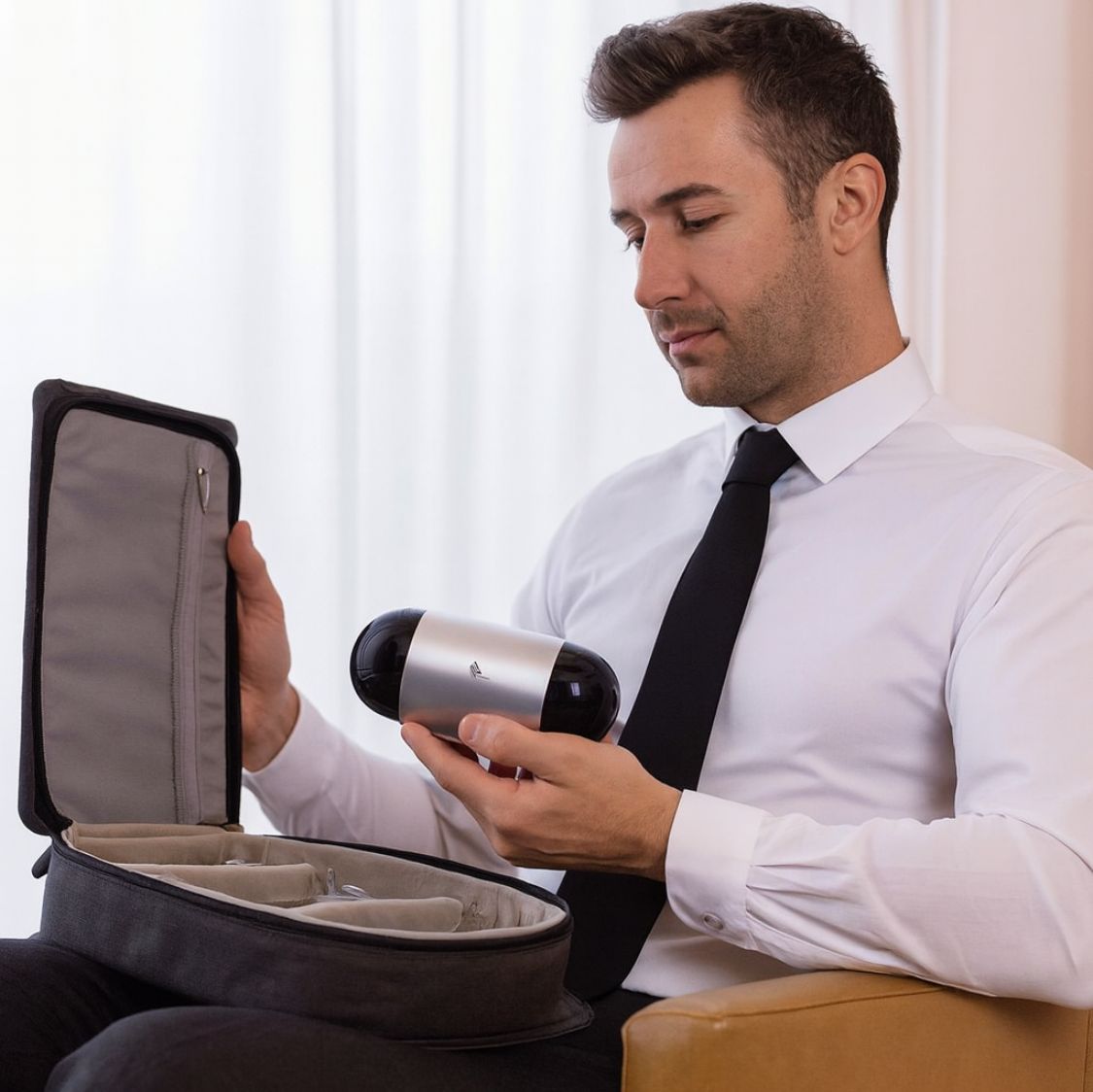 Compact CPAP in hand next to suitcase